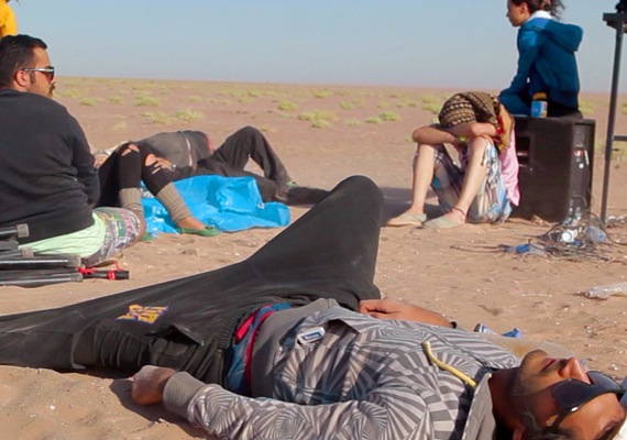 skupina lidí leží nebo sedí na slunci na písku